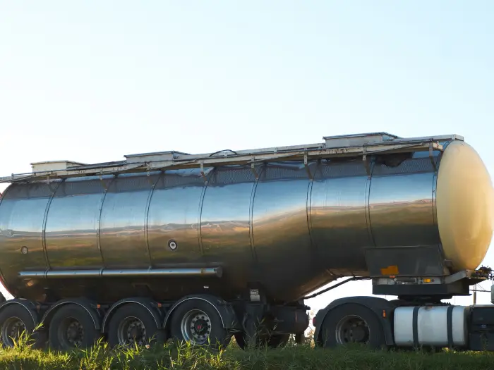 gasoline tank truck on the road with open cabine door and trucker in it. fuel and oil transportation